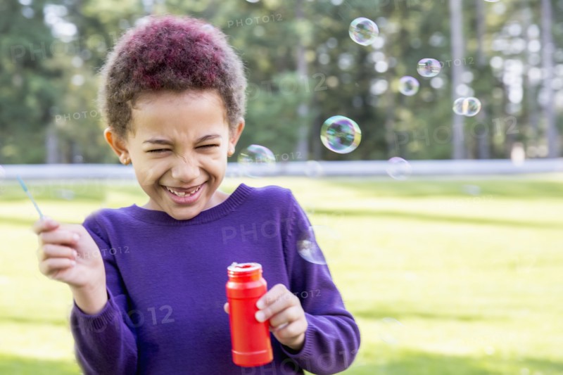 Mixed race girl blowing bubbles outdoors