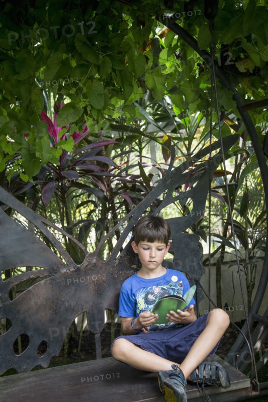 Caucasian boy reading on bench