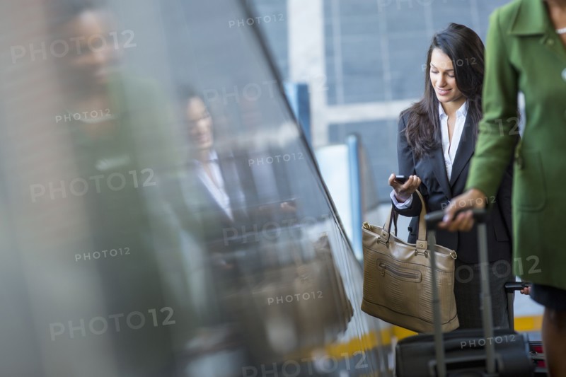 Mixed race businesswoman using cell phone on escalator