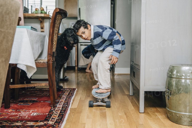 Mixed race boy riding skateboard in kitchen