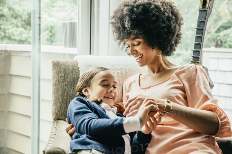 Mixed race mother holding daughter in armchair