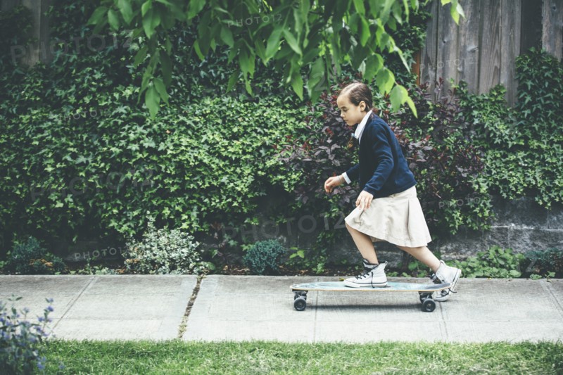 Mixed race girl riding skateboard on sidewalk