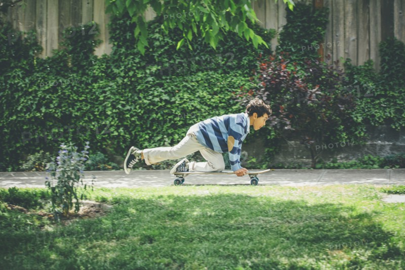 Mixed race boy riding skateboard on sidewalk