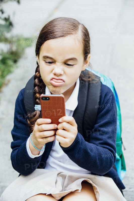 Mixed race girl making a face at cell phone