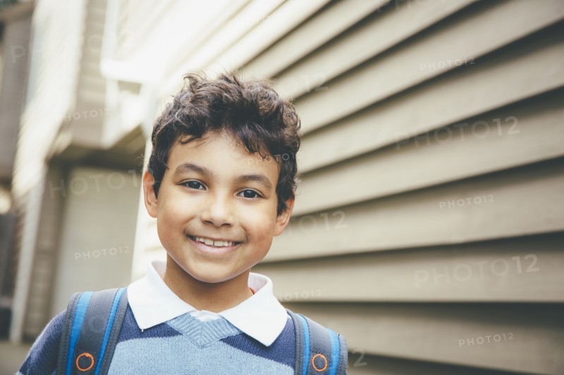 Mixed race boy smiling near house