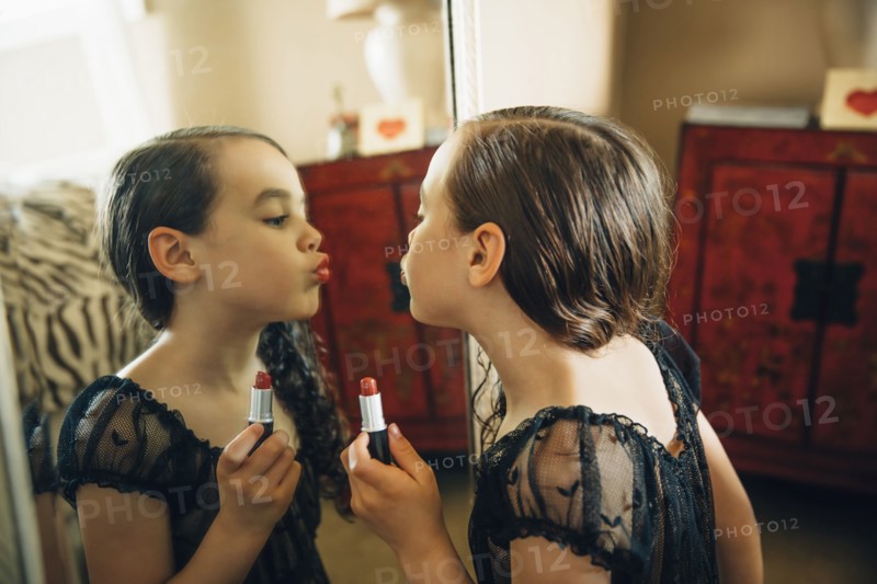 Mixed race girl applying lipstick in mirror