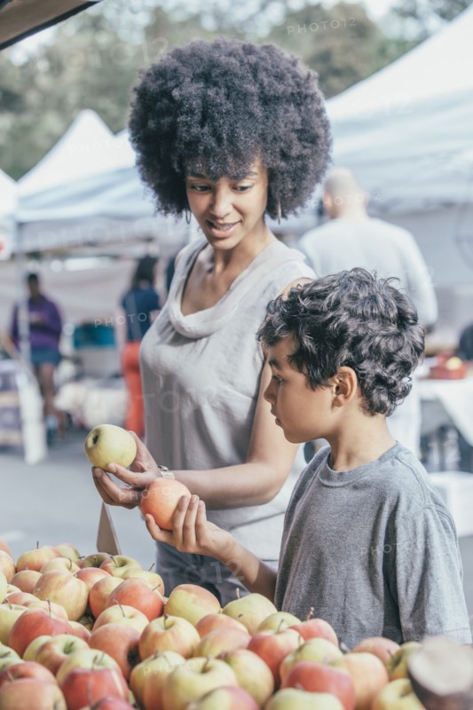 Mixed race boy shopping with mother at farmers market