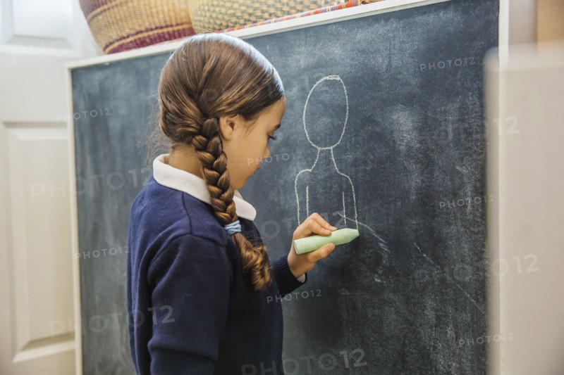 Mixed race girl drawing on chalkboard