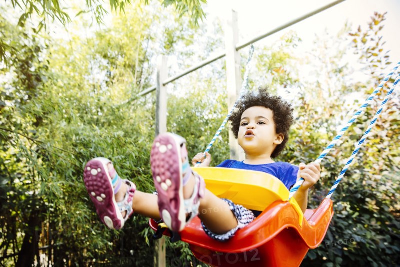 Low angle view of mixed race girl playing on swing