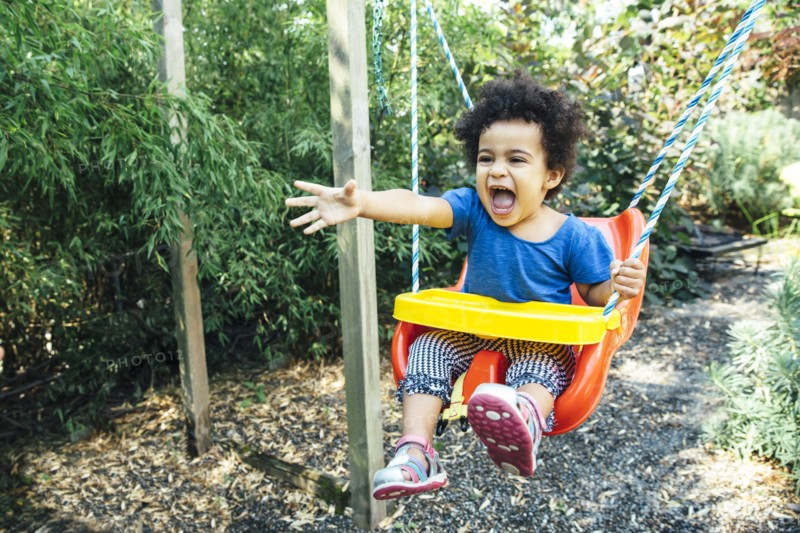 Low angle view of mixed race girl shouting on swing