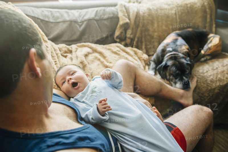 Caucasian father holding yawning baby boy in living room