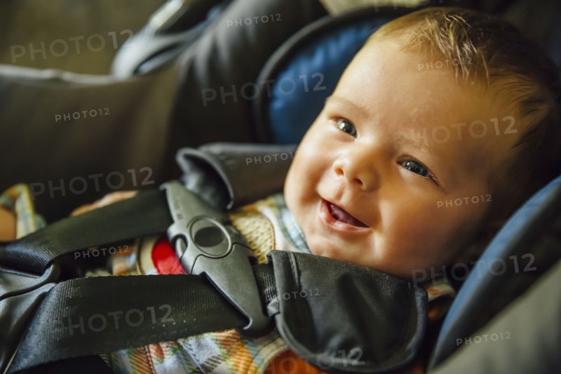 Caucasian baby boy smiling in car seat