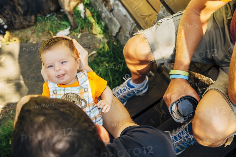 Caucasian gay couple relaxing with baby boy outdoors