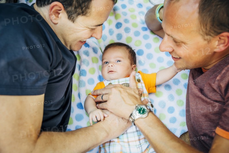 Caucasian gay couple cuddling baby boy