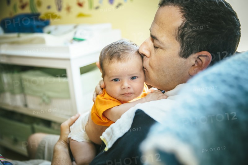 Caucasian father kissing baby boy in nursery