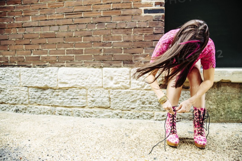 Caucasian woman tying boots on sidewalk