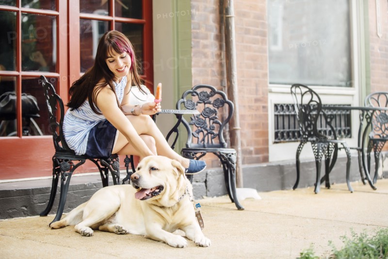Caucasian woman petting dog at sidewalk cafe
