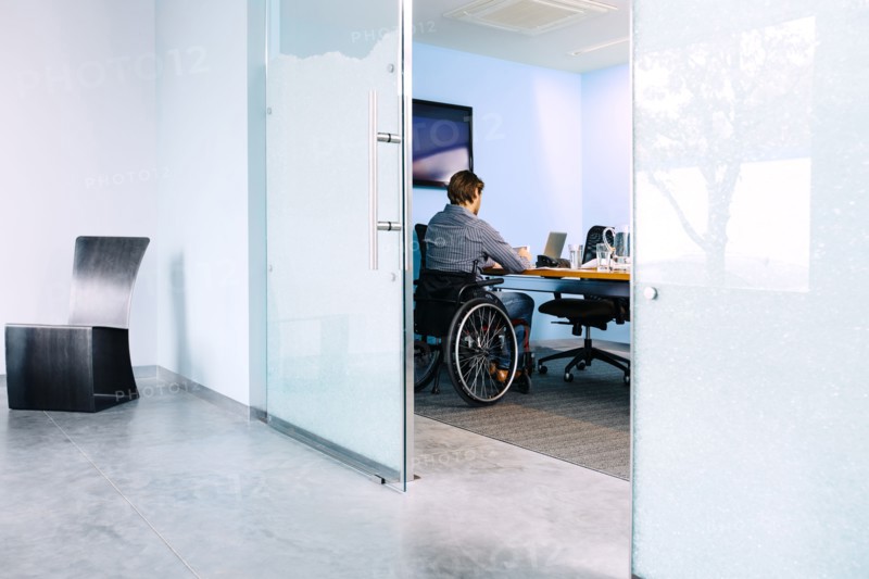 Businessman in wheelchair working at desk in office
