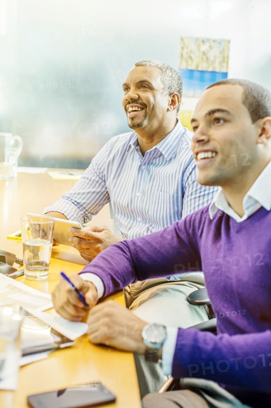 Businessmen laughing in office meeting