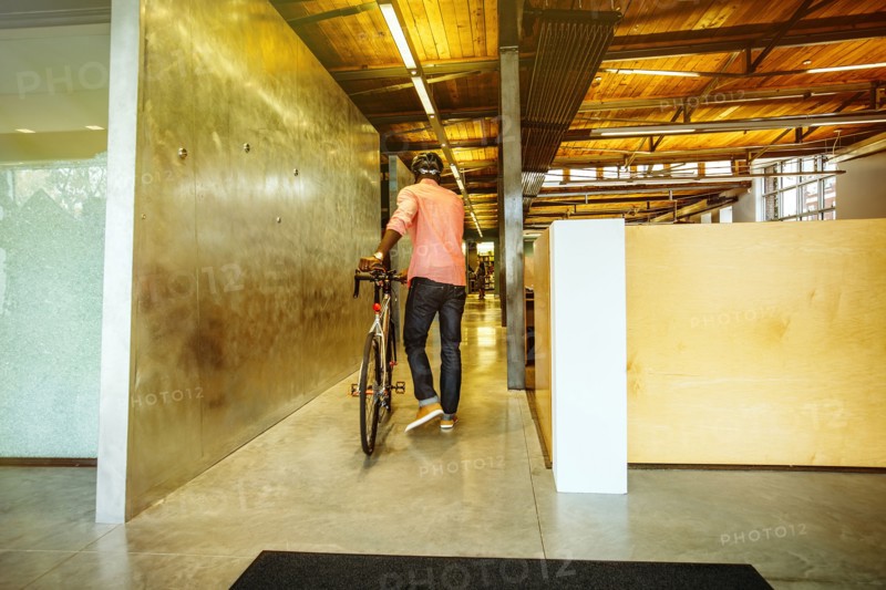 African American businessman pushing bicycle into office