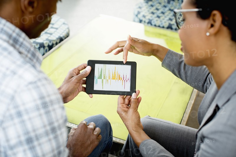 Black business people using digital tablet in office lobby