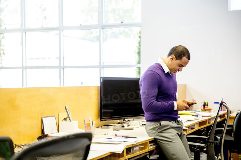 Mixed race businessman using cell phone at office desk