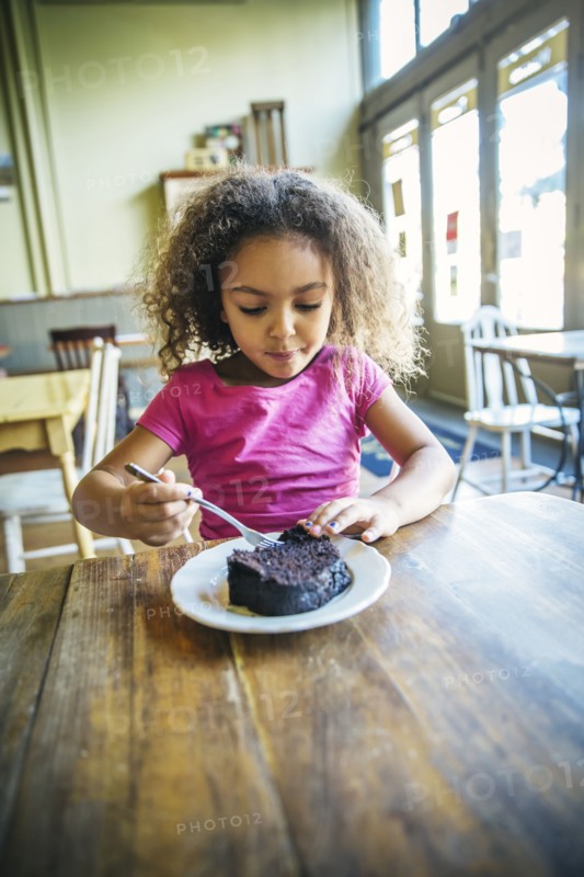 Mixed race girl eating dessert in cafe