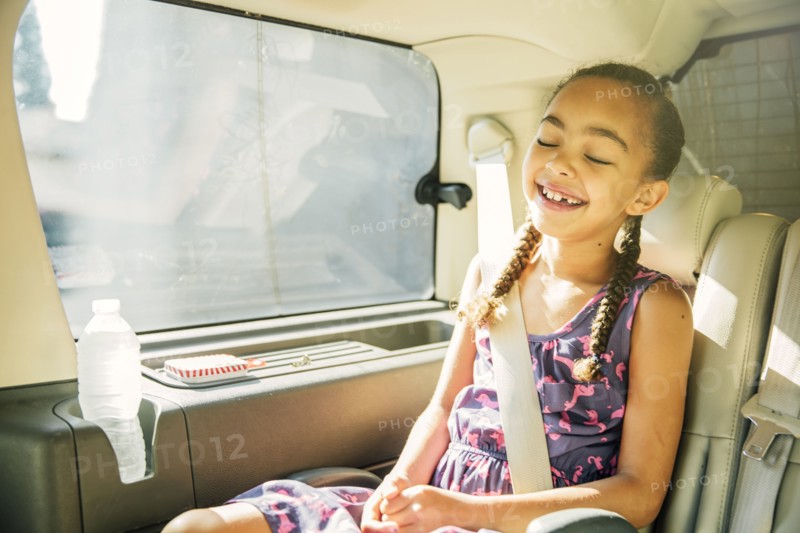 Mixed race girl smiling in back seat of car