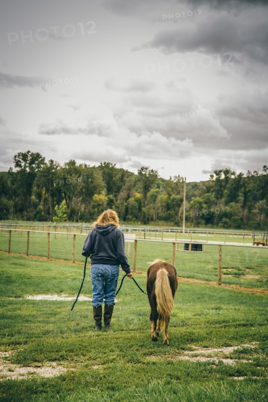 Caucasian woman walking miniature horse on ranch