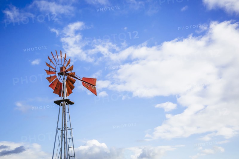 Low angle view of windmill turning under blue sky