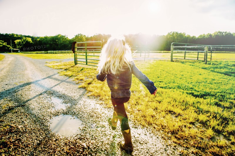 Caucasian girl walking on dirt road on ranch