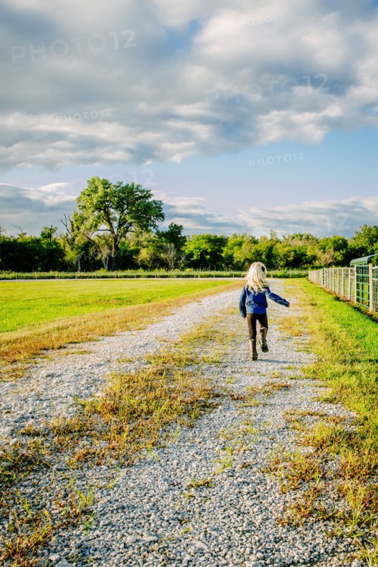 Caucasian girl walking on dirt road on ranch