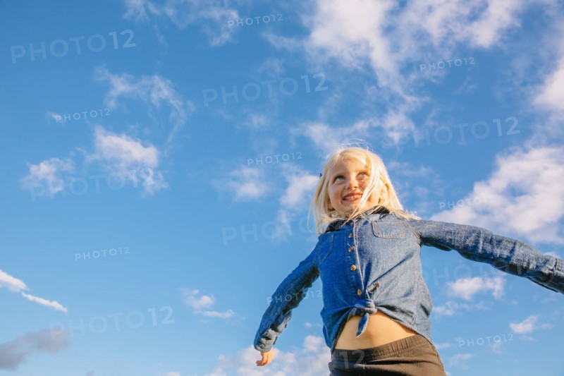 Low angle view of Caucasian girl standing under blue sky
