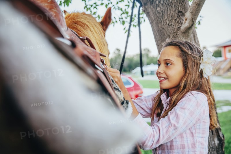 Caucasian girl fastening saddle on horse