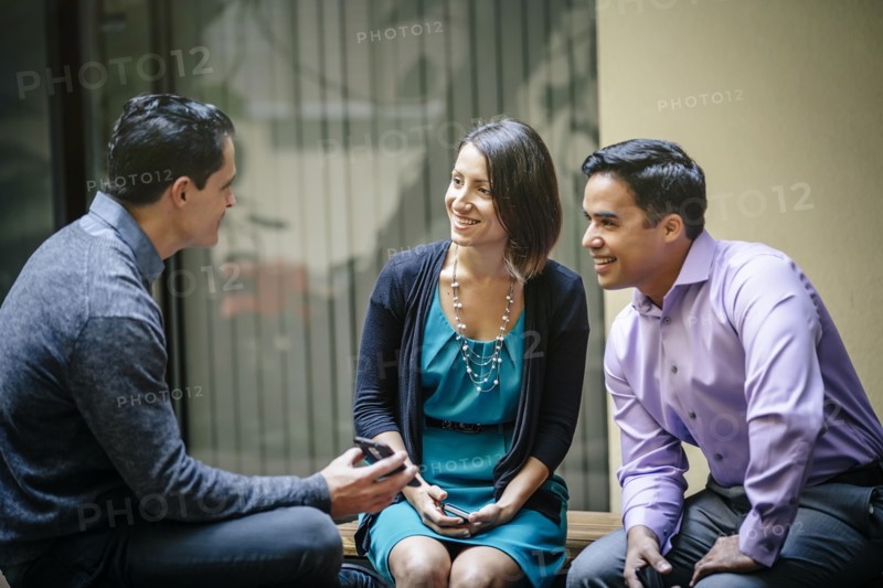 Business people using cell phone in office courtyard