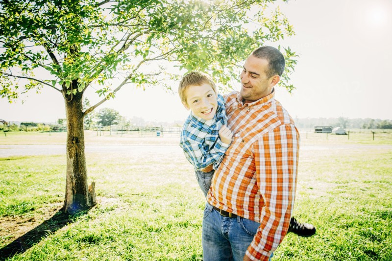 Smiling father carrying son on farm