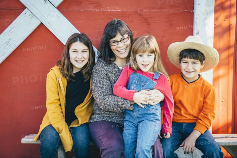 Caucasian mother and children smiling outside barn