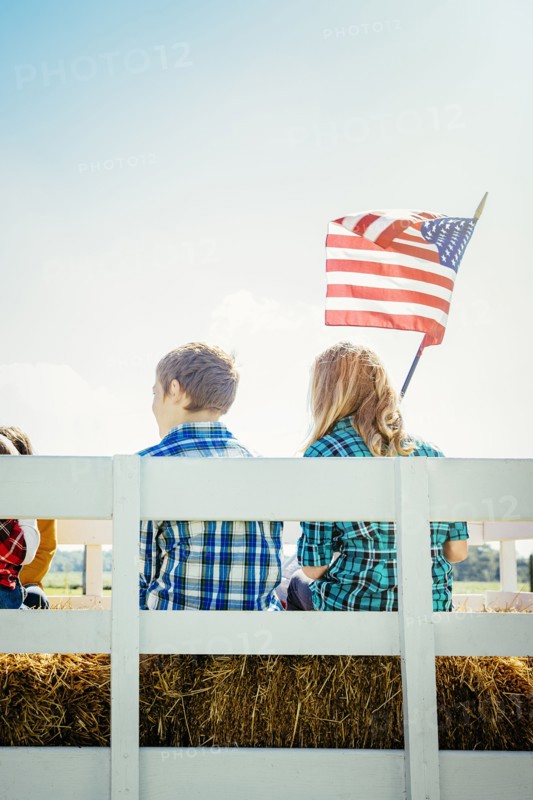 Caucasian children waving American flag on hay ride