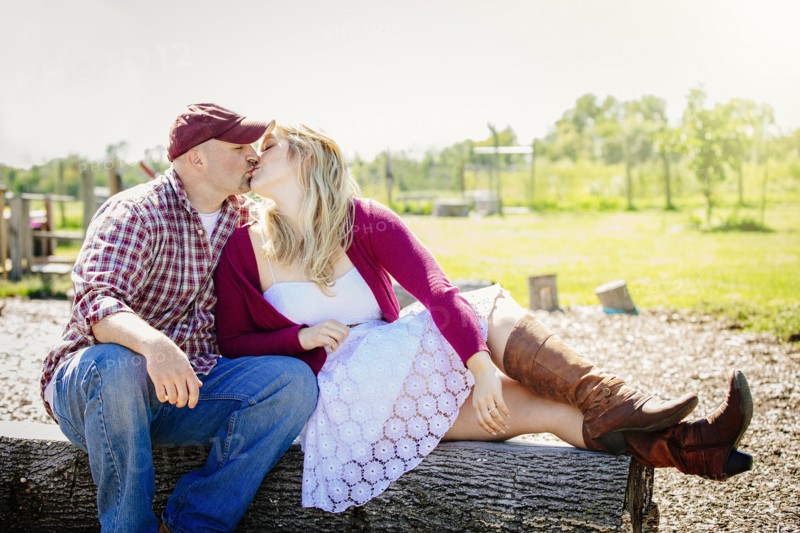 Caucasian couple kissing on wooden log in park
