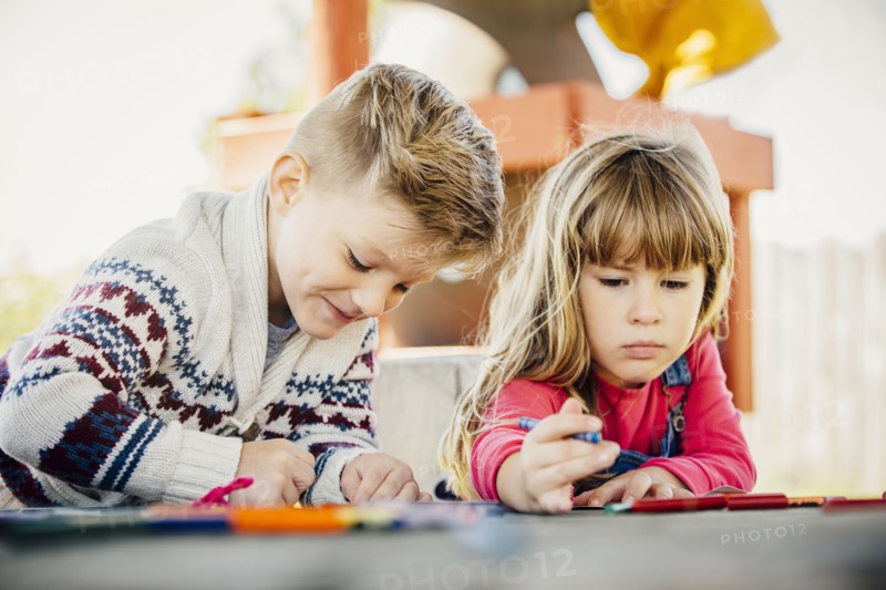 Caucasian brother and sister coloring outdoors