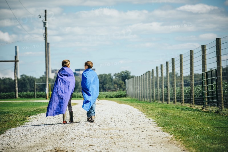Caucasian children wearing capes on dirt road