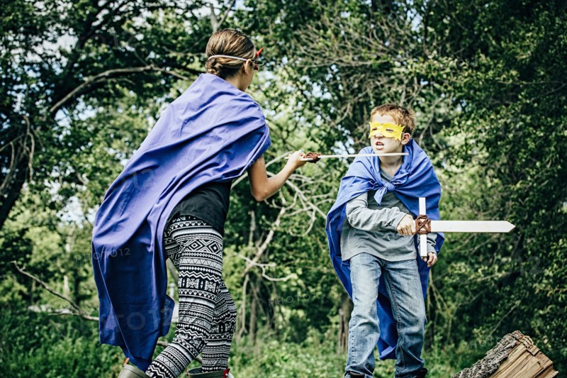 Caucasian children in costumes playing with swords