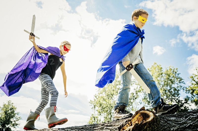 Caucasian children in costumes playing with swords