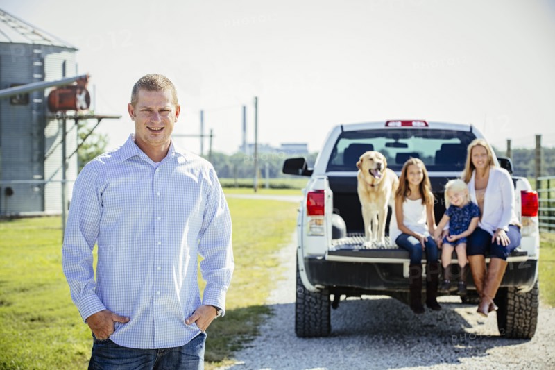 Caucasian man standing near family in truck bed