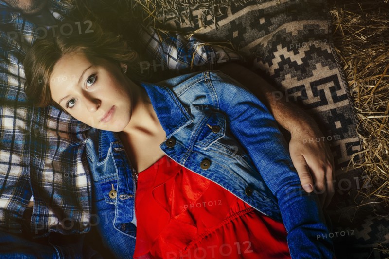 Caucasian woman laying with boyfriend on haystacks