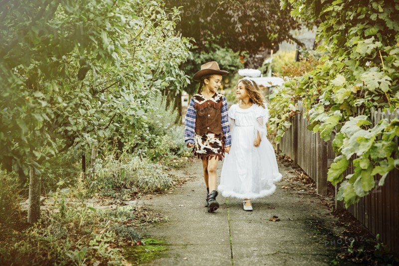 Sisters wearing Halloween costumes on sidewalk