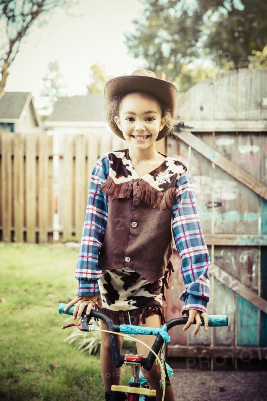 Mixed race girl wearing cowboy costume in backyard