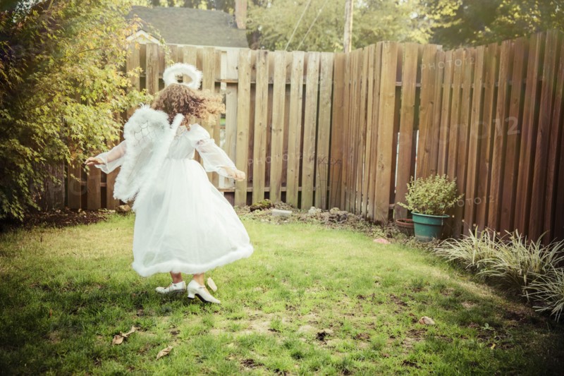 Mixed race girl wearing angel costume in backyard