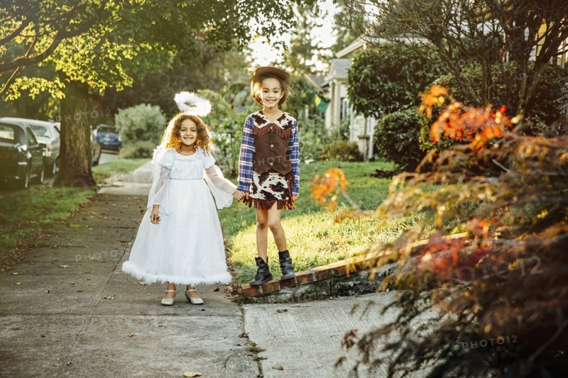 Sisters wearing Halloween costumes on sidewalk