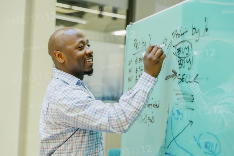 Black businessman writing on whiteboard